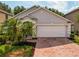 Exterior view of a single-story home showcasing a two-car garage and a brick paved driveway at 879 Nonastone Run, Casselberry, FL 32707