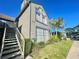 Two-story condo with beige siding, large windows, lush landscaping, and metal stairway on a clear, sunny day at 936 Birmingham Ct # 200, Lake Mary, FL 32746