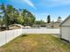 Fenced backyard with grass, neighboring buildings, and multiple trees in the background at 9821 8Th Ave, Orlando, FL 32824