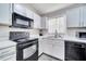 View of the well-lit kitchen featuring sleek, black appliances, bright white cabinets, and gray countertops at 9821 8Th Ave, Orlando, FL 32824