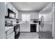 Galley kitchen with white cabinets, black appliances, and gray countertops at 9821 8Th Ave, Orlando, FL 32824