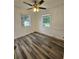 Bright bedroom with wood-look flooring, ceiling fan, and two windows at 985 N Village Dr, Deltona, FL 32725