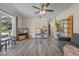 Bright living room with new flooring, a ceiling fan, and a large window overlooking the front yard at 985 N Village Dr, Deltona, FL 32725