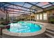 Inviting screened-in pool area featuring a spa, beautiful stone tiling, and serene landscaping views at 9873 Lost Creek Dr, Winter Garden, FL 34787