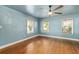 Bright bedroom featuring hardwood floors, three windows, and a contemporary ceiling fan at 1003 S Center St, Eustis, FL 32726