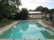 Backyard view of a refreshing rectangular swimming pool surrounded by lush landscaping and a fenced yard at 10208 Brownwood Ave, Orlando, FL 32825