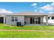 View of the backyard featuring a covered patio with outdoor seating, lush green grass, and AC unit at 1120 Mattie Pointe Blvd, Auburndale, FL 33823