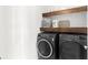 Modern laundry area with front load washer/dryer, open shelving, and neutral wall paint at 1120 Mattie Pointe Blvd, Auburndale, FL 33823