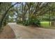 Long driveway leading to a home with a screened pool, amidst lush greenery and mature trees at 120 E Greentree Ln, Lake Mary, FL 32746