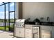 Outdoor kitchen features stainless steel appliances, a built-in grill, and a sink with a view of the backyard at 13822 Destin Beach Ln, Orlando, FL 32827