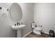 Stylish powder room with a pedestal sink, modern fixtures, and a decorative round mirror at 13822 Destin Beach Ln, Orlando, FL 32827