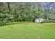 This grassy backyard features a storage shed and mature landscaping at 1576 Crosswind Cir, Orlando, FL 32825