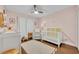 Charming Bedroom featuring a white crib, plush rug, and soothing pink walls at 1576 Crosswind Cir, Orlando, FL 32825