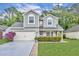 Charming two-story home featuring a manicured lawn, gray siding, and an attached two-car garage at 1576 Crosswind Cir, Orlando, FL 32825