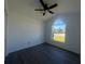 Bedroom with gray floors, ceiling fan, and large window offering neighborhood view at 215 Hollowbrook Cir, Daytona Beach, FL 32114