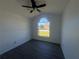 Bedroom with vaulted ceiling, gray floors, ceiling fan, and large window for natural light at 215 Hollowbrook Cir, Daytona Beach, FL 32114