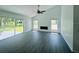 Bright living room with vaulted ceiling, fan, gray wood-look flooring, sliding glass door to yard, and fireplace at 215 Hollowbrook Cir, Daytona Beach, FL 32114