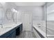 Bright bathroom featuring double sinks, oval mirrors, soaking tub with subway tile, and gray tile floors at 2325 Bella Luna Cir, Lakeland, FL 33810
