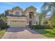 Well-maintained two story house featuring brick driveway, two car garage, and manicured landscaping at 33919 Terragona Dr, Sorrento, FL 32776