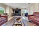 Bright living room with leather sofas, modern entertainment center, and large windows offering natural light at 33919 Terragona Dr, Sorrento, FL 32776
