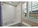 Bright bathroom featuring a soaking tub with tile surround and shuttered windows at 3725 Calabria Ave, Davenport, FL 33897
