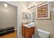 Bright bathroom features vanity storage, decorative mirror, a toilet, and a hardwood floor entry at 3725 Calabria Ave, Davenport, FL 33897