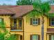 Exterior of a two-story home with yellow siding, balcony, and a decorative palm tree at 3725 Calabria Ave, Davenport, FL 33897