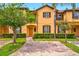 Charming two-story townhome featuring a yellow facade, brown accents, and well-manicured landscaping at 3725 Calabria Ave, Davenport, FL 33897