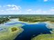 Stunning aerial view capturing a dark blue lake surrounded by lush green vegetation and lily pads at 4055 State Road 11, Deland, FL 32724