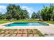 Backyard pool with brick trim, grass, lake view, mature trees and outdoor seating at 4055 State Road 11, Deland, FL 32724