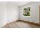 Neutral bedroom with wood-look flooring, white walls, and a view of the backyard through the window at 4770 Drummond Ln, Orlando, FL 32810