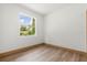 Bright bedroom with wood-look flooring, white walls, a view of the greenery outside the window, and neutral trim at 4770 Drummond Ln, Orlando, FL 32810