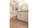 Bathroom with white vanity, granite countertop, decorative mirror, updated fixtures, and wood-look flooring at 4963 Hoperita St, Orlando, FL 32812