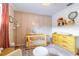 Stylish Bedroom featuring a crib, a changing table, soft rugs, a patterned accent wall, and a colorful toy shelf at 4963 Hoperita St, Orlando, FL 32812