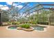 Beautiful screened-in pool with lush tropical plants, decorative rock features, and inviting lounge area at 5241 Vista Club Run, Sanford, FL 32771