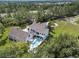 An aerial view showcases a grand estate with a pristine pool area, surrounded by lush greenery and mature trees at 5351 Carson St, St Cloud, FL 34771