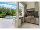 Outdoor kitchen area, perfect for entertaining, with a built-in grill, pool and stainless steel refrigerator at 5351 Carson St, St Cloud, FL 34771