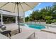 A serene pool area features a large umbrella, tiled deck, and comfortable seating, perfect for outdoor relaxation at 5351 Carson St, St Cloud, FL 34771