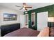 Primary bedroom with a decorative green accent wall, television, and ceiling fan at 5515 Palomino Pl, Apopka, FL 32712