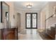 Elegant foyer with tile flooring, staircase, wrought iron door, and decorative furnishings at 6149 Blakeford Dr, Windermere, FL 34786