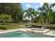 Beautiful pool and spa with manicured landscaping, a black fence, and serene water views at 6149 Blakeford Dr, Windermere, FL 34786