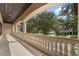 Covered porch with white columns, stone railing, and brick flooring overlooking the well-manicured lawn at 6149 Blakeford Dr, Windermere, FL 34786