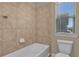 Cozy bathroom boasts a tiled tub and a toilet with a window allowing natural light in at 8348 Vivaro Isle Way, Windermere, FL 34786