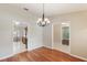 Dining room featuring hardwood floors, a modern chandelier, and views into the kitchen and other rooms at 957 Yellow Rose Dr, Orlando, FL 32818
