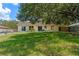 Open backyard showing the home exterior, patio, and lush lawn with mature trees at 10739 Lake Ralph Dr, Clermont, FL 34711