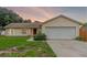 Well-kept single-story home with an attached two-car garage and a vibrant red door, set against a colorful sky at 10739 Lake Ralph Dr, Clermont, FL 34711