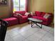 Cozy living room featuring bright red sofa, love seat, and a unique glass-topped coffee table at 10739 Lake Ralph Dr, Clermont, FL 34711