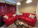 Cozy living room featuring two red couches, a glass coffee table, and natural light from a nearby window at 10739 Lake Ralph Dr, Clermont, FL 34711