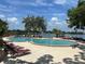 Gorgeous community pool overlooking a serene lake, complete with lounge chairs and tropical landscaping at 1252 Lake Willisara Cir # Ge, Orlando, FL 32806