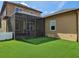 Backyard featuring a lush, green lawn, screened-in porch, and a view of the home's exterior at 1414 Stickley Ave, Kissimmee, FL 34747
